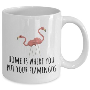 May include: White ceramic coffee mug with a pink flamingo design and the text "Home is where you put your flamingos".