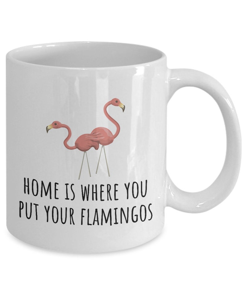 May include: White ceramic coffee mug with a pink flamingo design and the text "Home is where you put your flamingos".