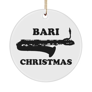 Pode incluir: Enfeite de Natal de cerâmica branca com fio dourado. O enfeite apresenta as palavras "BARI CHRISTMAS" em preto, com uma silhueta de saxofone preto no centro.