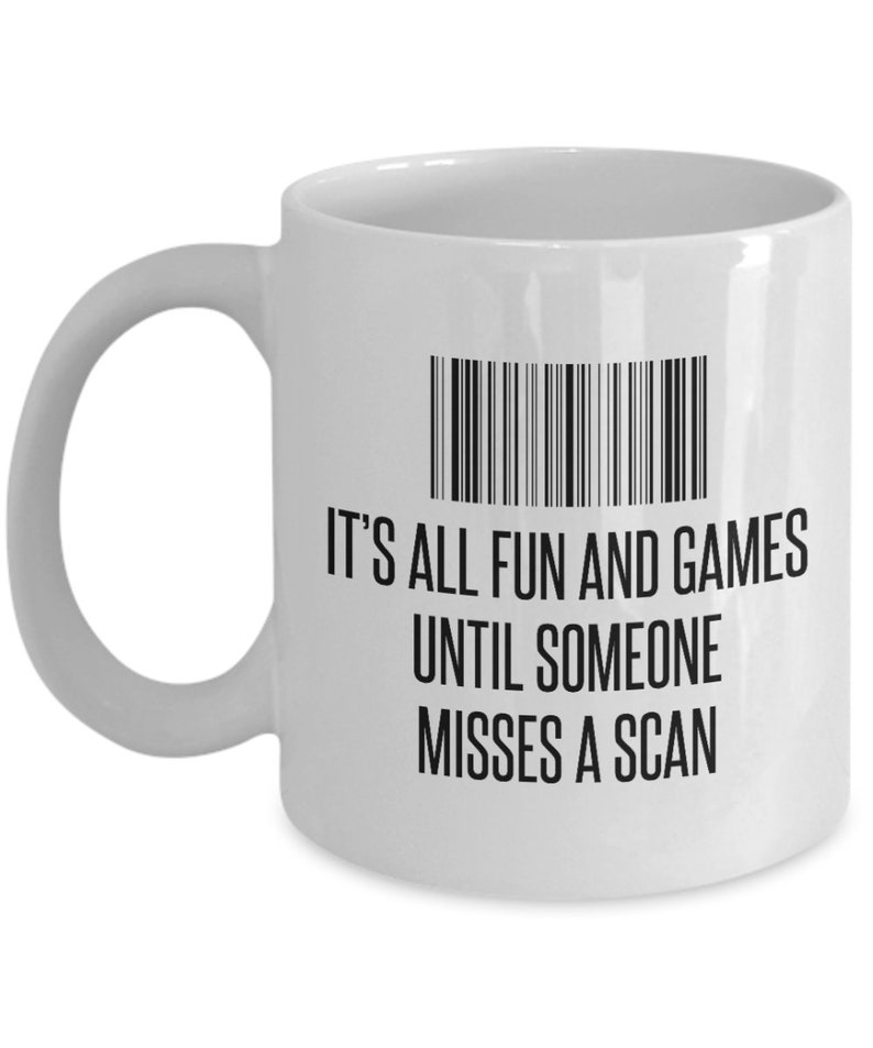 May include: White ceramic mug with a black barcode graphic and the text "IT'S ALL FUN AND GAMES UNTIL SOMEONE MISSES A SCAN". The mug has a curved handle and is suitable for hot or cold beverages.