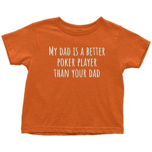 May include: Orange short-sleeved t-shirt with white text that reads "My dad is a better poker player than your dad."