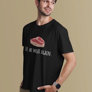 May include: Black t-shirt with a white graphic of a steak and the text "So, we meat again."