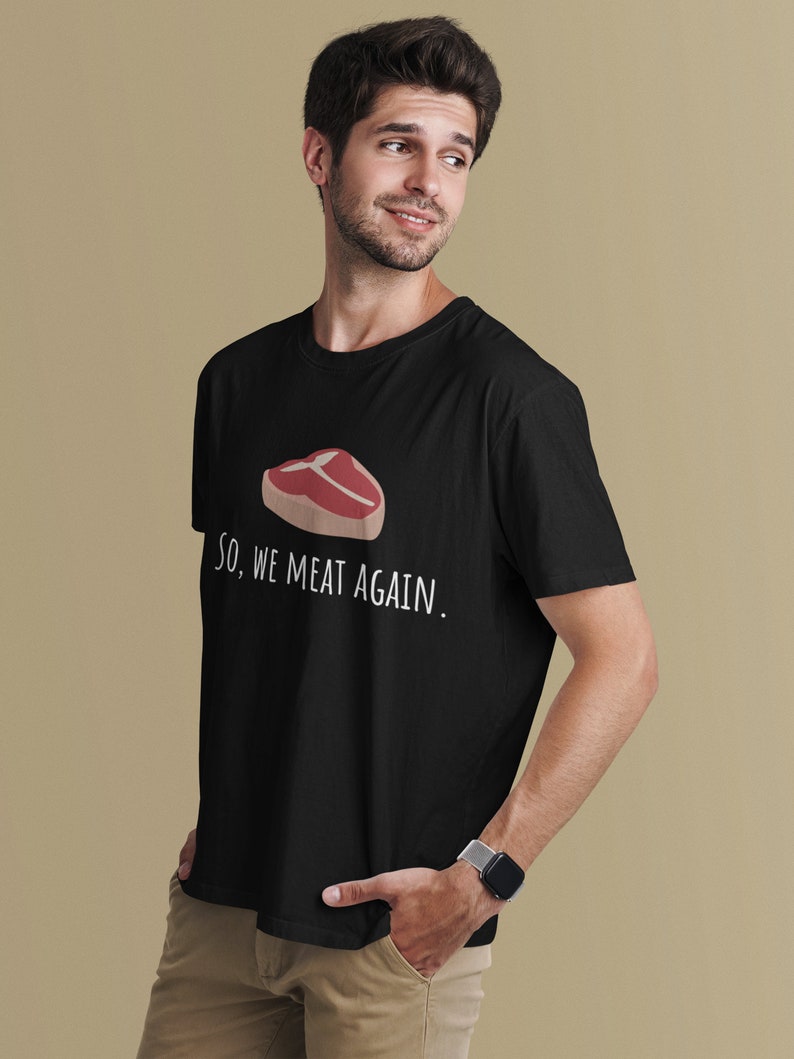 May include: Black t-shirt with a white graphic of a steak and the text "So, we meat again."