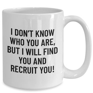 May include: White ceramic mug with a curved handle. The mug features black text that reads: "I DON'T KNOW WHO YOU ARE, BUT I WILL FIND YOU AND RECRUIT YOU!" A humorous gift for a recruiter or hiring manager.