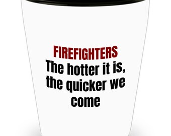 Puede incluir: Un vaso de chupito de cerámica blanca con un borde negro. El texto "FIREFIGHTERS The hotter it is, the quicker we come" está impreso en negro en el vaso.