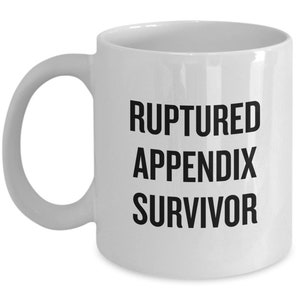 Peut inclure: Une tasse à café en céramique blanche avec du texte noir qui dit "Ruptured Appendix Survivor".