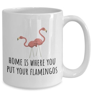 May include: White ceramic coffee mug with a pink flamingo illustration and the text "Home is where you put your flamingos".