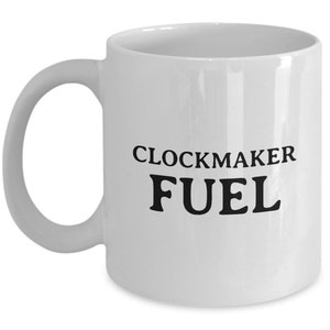 Puede incluir: Taza de café de cerámica blanca con texto negro que dice "CLOCKMAKER FUEL".