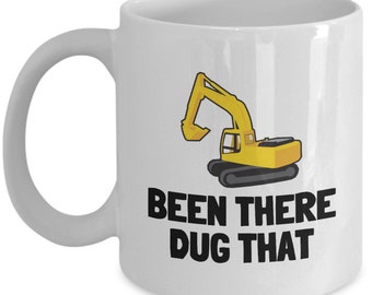 May include: White ceramic coffee mug featuring a yellow excavator illustration and the text "Been There Dug That" in black.