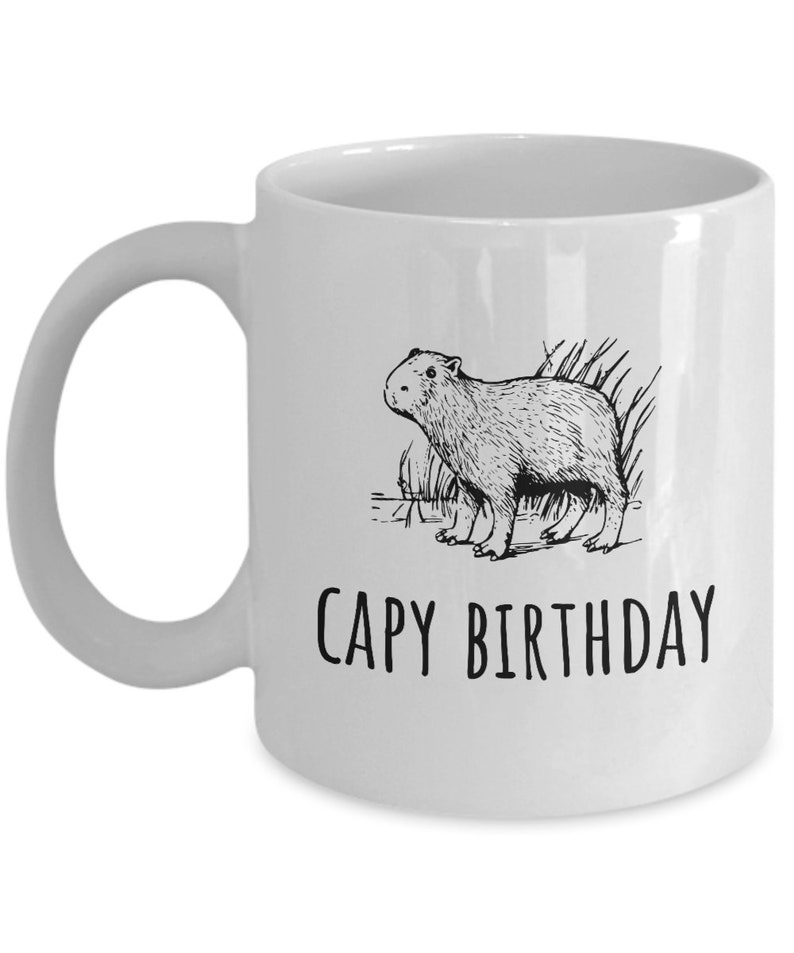 May include: White ceramic coffee mug with a black line drawing of a capybara and the text "CAPY BIRTHDAY" printed on the front.