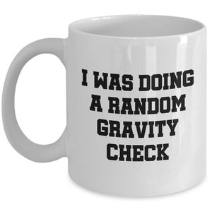 May include: White ceramic coffee mug with black text that reads "I was doing a random gravity check".