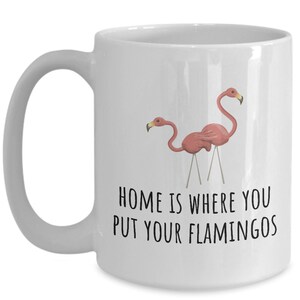 May include: White ceramic coffee mug with a pink flamingo design and the text "Home is where you put your flamingos".