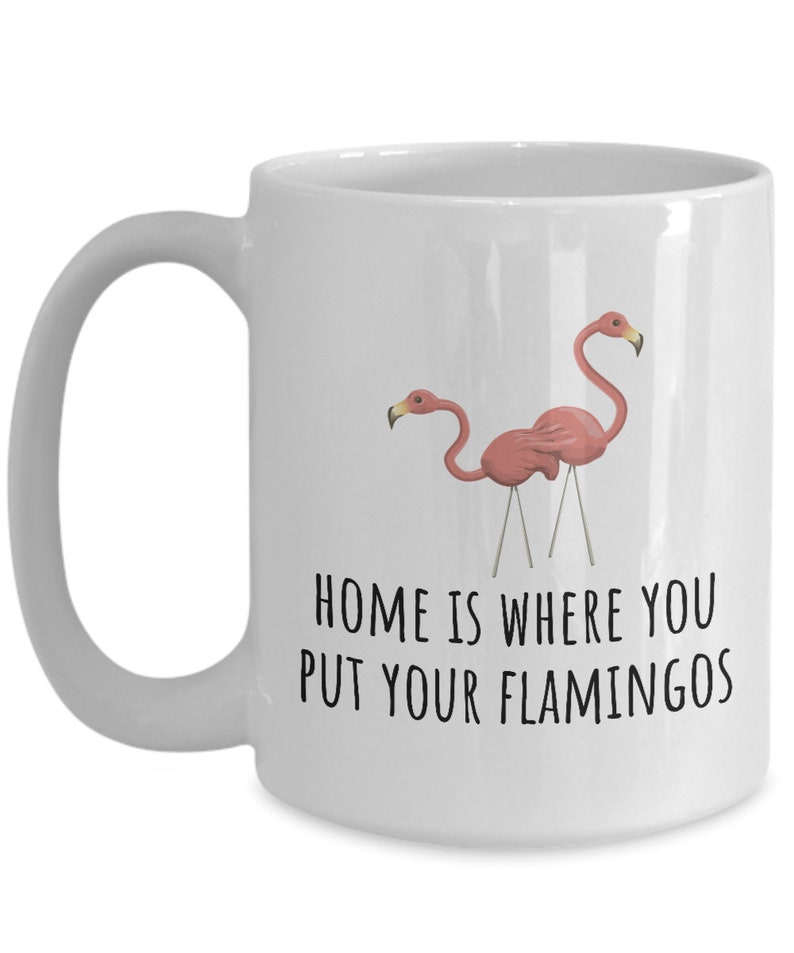 May include: White ceramic coffee mug with a pink flamingo design and the text "Home is where you put your flamingos".
