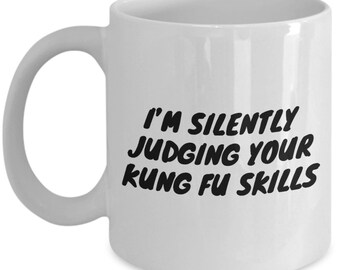 Puede incluir: Taza de café de cerámica blanca con texto negro que dice "Estoy juzgando silenciosamente tus habilidades de kung fu".