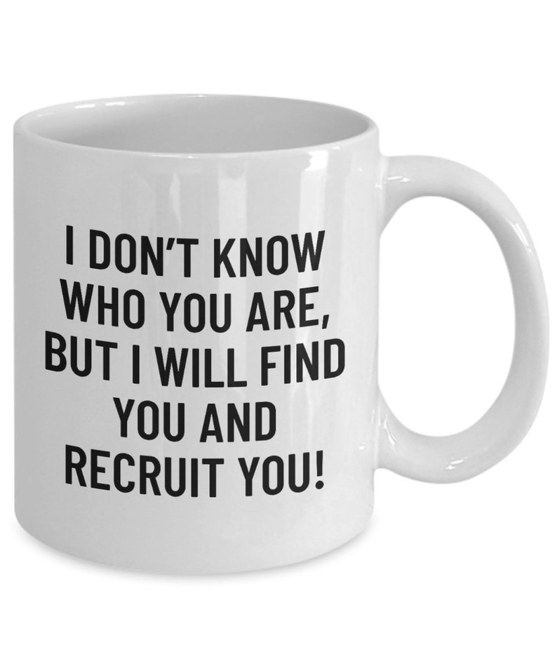 May include: White ceramic mug with a curved handle. The mug features black text that reads: "I DON'T KNOW WHO YOU ARE, BUT I WILL FIND YOU AND RECRUIT YOU!" A humorous gift for a recruiter or hiring manager.