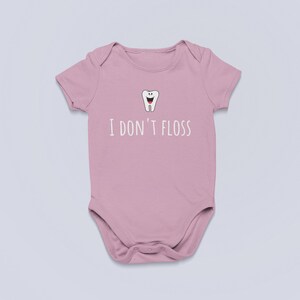 Peut inclure: Une grenouill&egrave;re rose pour b&eacute;b&eacute; avec une dent de dessin anim&eacute; blanche et le texte "Je ne passe pas de fil dentaire".