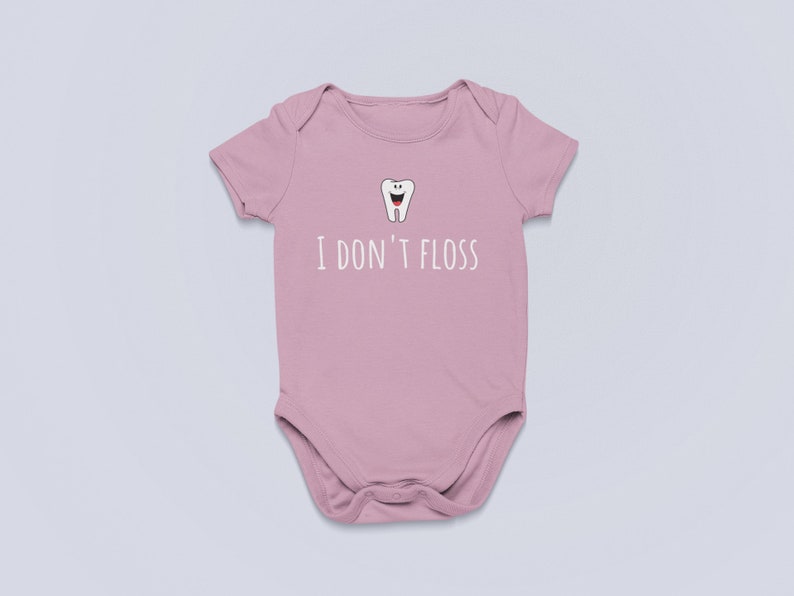 Peut inclure: Une grenouill&egrave;re rose pour b&eacute;b&eacute; avec une dent de dessin anim&eacute; blanche et le texte "Je ne passe pas de fil dentaire".