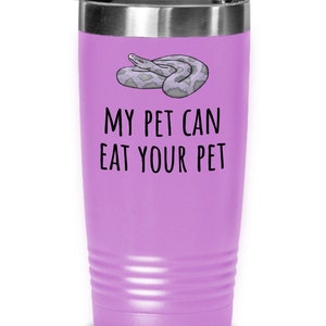 Puede incluir: Un vaso de viaje lila con tapa plateada. El vaso presenta una ilustración de dibujos animados de una serpiente y el texto "MY PET CAN EAT YOUR PET" en negro. El vaso está diseñado con una textura acanalada.