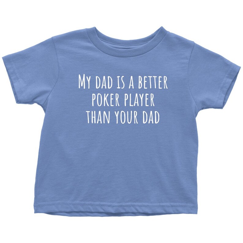 May include: A light blue toddler t-shirt with the text "My Dad is a Better Poker Player Than Your Dad" printed in white.