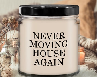 Peut inclure: Une bougie en pot de verre avec un couvercle noir. La bougie a une cire de couleur crème et porte l'inscription "NEVER MOVING HOUSE AGAIN" en noir. La bougie est posée sur un fond doux et neutre avec des éléments décoratifs.