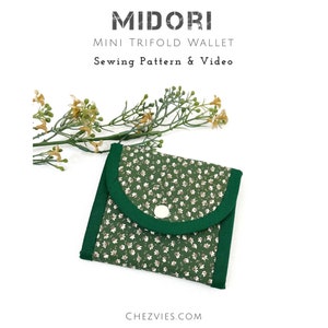 May include: A small green trifold wallet with a white floral pattern and a green button closure. The wallet is made of fabric and is a sewing pattern and video tutorial.