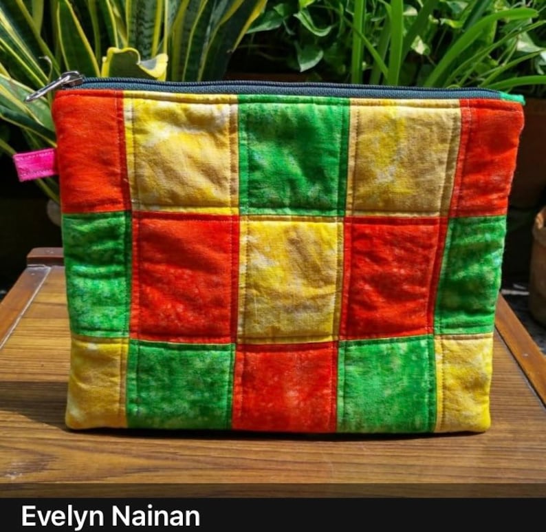 K&ouml;nnte beinhalten: Eine gr&uuml;ne, rote und gelbe Patchwork-Kosmetiktasche mit Rei&szlig;verschluss. Die Tasche besteht aus zusammengen&auml;hten Stoffquadraten.