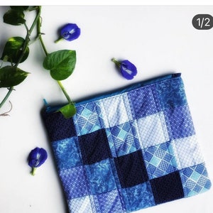 K&ouml;nnte beinhalten: Eine blaue und wei&szlig;e Patchwork-Kosmetiktasche mit Karomuster. Die Tasche besteht aus Stoffresten, die in einem Quilt-&auml;hnlichen Stil zusammengen&auml;ht wurden.