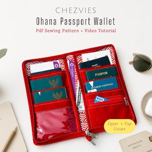 Op de afbeelding: Rode Ohana paspoort portemonnee met meerdere compartimenten, waaronder een vak met ritssluiting en doorzichtige ID-sleuven. De portemonnee is open en toont paspoorten en kaarten. Tekst op de portemonnee luidt "Ohana Passport Wallet" en "Zipper + Flap Closure".