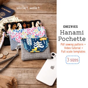May include: Three wristlet wallets in various patterns: a chess-themed design, a floral print, and a blue and white tree design. The wallets are displayed on a wooden surface with a passport, money, and a smartphone.