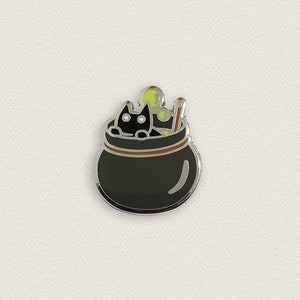 May include: Black cat sitting in a black cauldron with green steam and a brown wooden stirring stick.