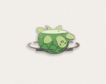 May include: A green pineapple-shaped pin with a smiling face and musical notes, spinning on a silver ring.
