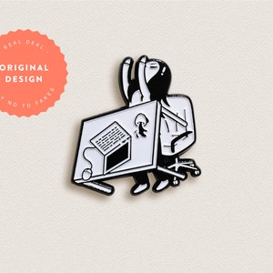 Könnte beinhalten: Schwarze und weiße Emaille-Anstecknadel mit einer Person, die an einem Schreibtisch mit einem Computer, einer Maus und einer Kaffeetasse sitzt. Der Text "REAL DEAL ORIGINAL DESIGN SAY NO TO FAKES" befindet sich auf einem rosa Kreis.