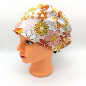 Puede incluir: Un gorro quirúrgico Euro blanco con un estampado floral retro en naranja, amarillo y rosa. El gorro presenta un diseño clásico con un ajuste cómodo. El texto "Euro Scrub Cap" se muestra en la parte inferior de la imagen.