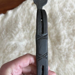 Pode incluir: Uma maçaneta de porta de metal preto em forma de ferradura com um design decorativo. A maçaneta tem uma parte superior redonda com um furo no centro.