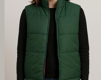 May include: A green puffer vest with a red interior lining. The vest has a high collar and a full-length zipper. The vest is worn over a black long-sleeved shirt.