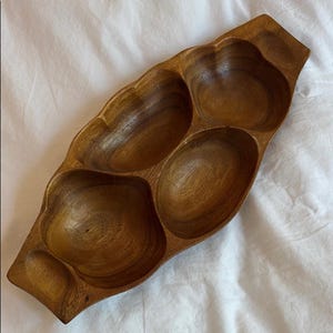 May include: A wooden serving platter with four sections. The dark brown wood tray has an unusual, flowing form. The compartments are different sizes and shapes, ideal for serving snacks or appetizers. The tray is made of wood.