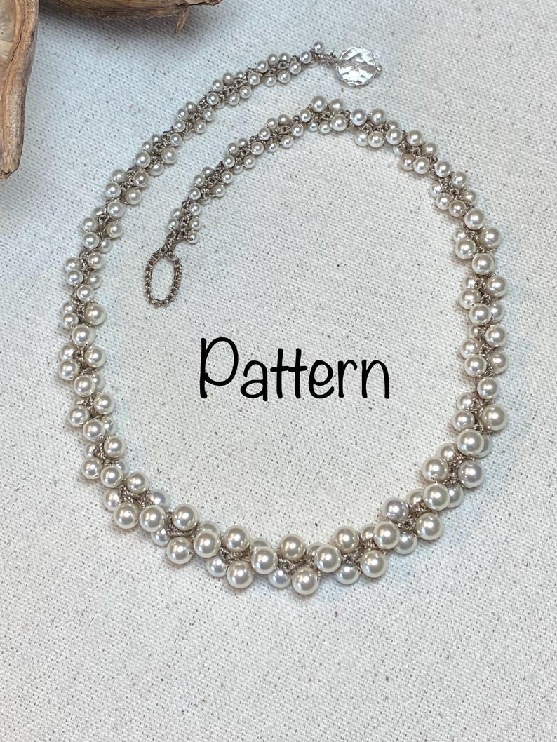 May include: A white pearl necklace with a silver clasp. The necklace is made of two strands of pearls, with the pearls arranged in a pattern of alternating rows.