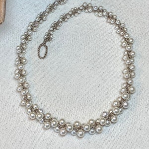 May include: A delicate silver necklace with a double strand of white pearls. The pearls are arranged in a staggered pattern, creating a unique and elegant look.