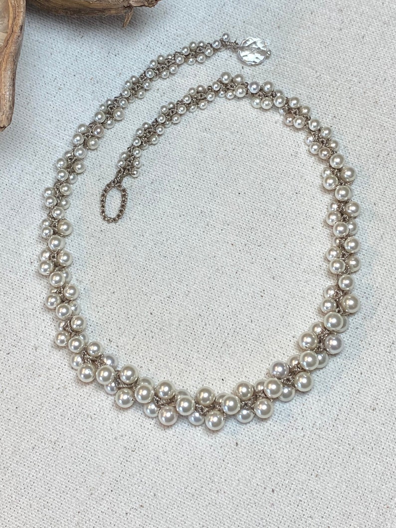 May include: A delicate silver necklace with a double strand of white pearls. The pearls are arranged in a staggered pattern, creating a unique and elegant look.