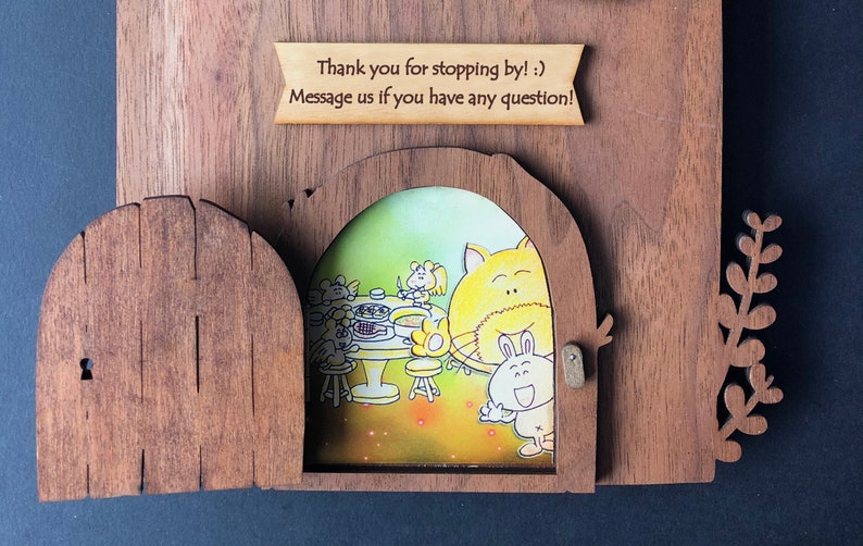 May include: A wooden door with a keyhole opens to reveal a whimsical illustration of a cat and bunny enjoying a meal with other animals. The text "Thank you for stopping by! :) Message us if you have any question!" is written on a wooden sign above the door.