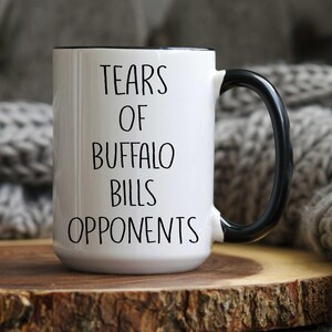May include: White ceramic coffee mug with a black handle and black text that reads "Tears of Buffalo Bills Opponents".