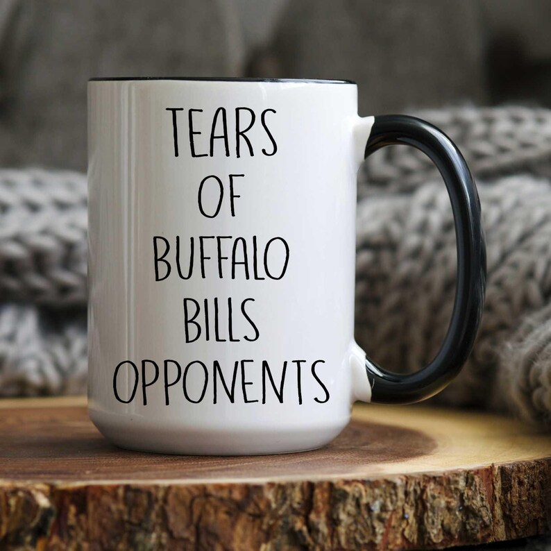 May include: White ceramic coffee mug with a black handle and black text that reads "Tears of Buffalo Bills Opponents".