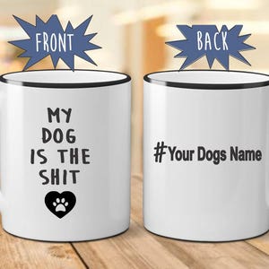 May include: White ceramic coffee mug with a black rim and handle. The front of the mug reads "My Dog Is The Shit" with a paw print heart. The back of the mug has a black hashtag and the text "Your Dogs Name".