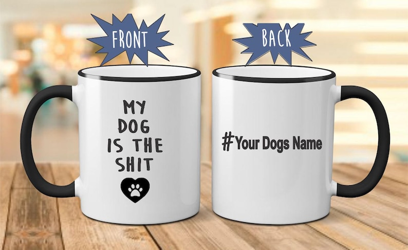 May include: White ceramic coffee mug with a black rim and handle. The front of the mug reads "My Dog Is The Shit" with a paw print heart. The back of the mug has a black hashtag and the text "Your Dogs Name".
