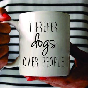 May include: White ceramic mug with black text that reads "I prefer dogs over people".