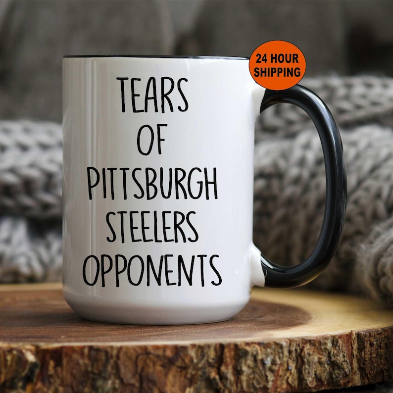 K&ouml;nnte beinhalten: Wei&szlig;e Keramik-Kaffeetasse mit schwarzem Henkel und schwarzem Rand. Die Tasse tr&auml;gt den Text "Tears of Pittsburgh Steelers Opponents" in schwarzer Schrift.