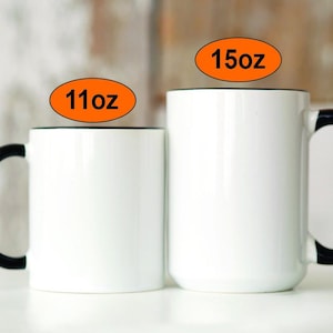 Puede incluir: Dos tazas de cer&aacute;mica blanca con asas negras. La taza de la izquierda es de 11 oz y la taza de la derecha es de 15 oz.