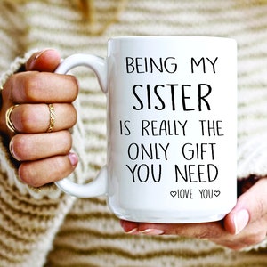 May include: White ceramic mug with black text that reads "Being my sister is really the only gift you need. Love you."