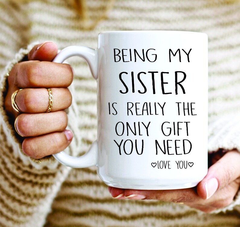 May include: White ceramic mug with black text that reads "Being my sister is really the only gift you need. Love you."