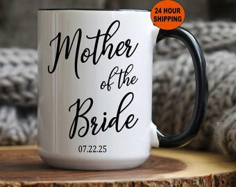 May include: White ceramic mug with a black rim and handle. The mug has black text that reads "Mother of the Bride" and the date "07.22.25".